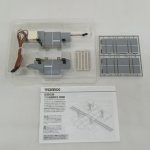 透明ケースに入った踏切のユニット2組と、灰色の部品の枠、TOMIXの説明書を並べた写真。