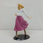 フィギュアの全身を斜め前から写したもの。白い上着と赤紫のスカート、黒い円形の台座