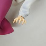赤紫のスカートの端と、袖から出た手のアップ
