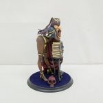 フィギュアを正面から撮った写真。褐色の肌の女性と、積み重なった本の飾りが台座に付いています。