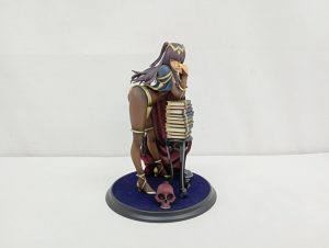 フィギュアを正面から撮った写真。褐色の肌の女性と、積み重なった本の飾りが台座に付いています。