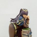 上半身を寄せて撮った写真。顔と手、積まれた本が写っています。
