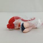 本体を斜め後ろから。長い赤い髪と背中、袋がかかった状態。