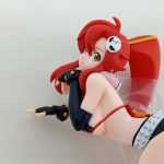 本体の上半身を横から。赤い髪と黒い手袋、袋に包まれた状態で写っています。