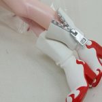 足元のアップ。炎の柄が入った白いブーツと、袋越しの脚。