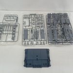 袋に入った灰色のランナーと、紺色の板状の部品