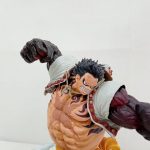 フィギュアの上半身のアップ。歯を食いしばった表情と白いマント、黒い腕