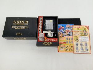 外箱と中箱、ライターと金属パーツ、ルパン三世のチラシ2枚を並べた様子