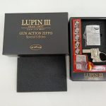 外箱と内箱を並べた写真。LUPIN III GUN ACTION ZIPPOの文字、ライターとガン型の台座