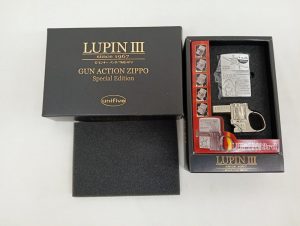 外箱と内箱を並べた写真。LUPIN III GUN ACTION ZIPPOの文字、ライターとガン型の台座